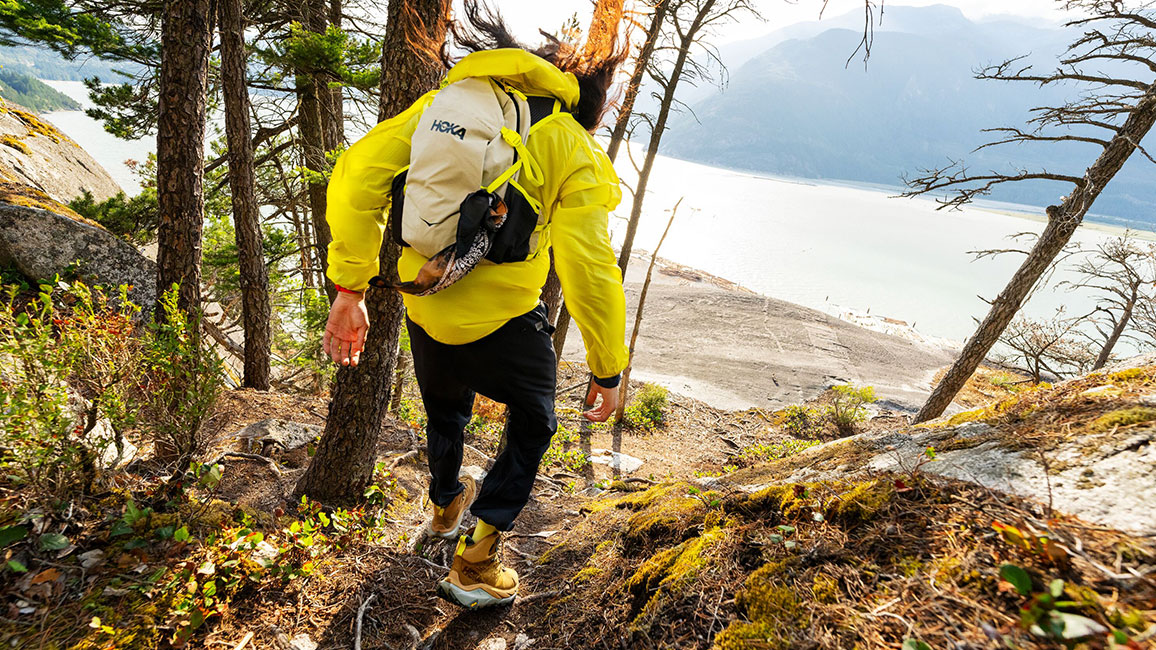 a man hiking in a yellow jacket with a backpack on