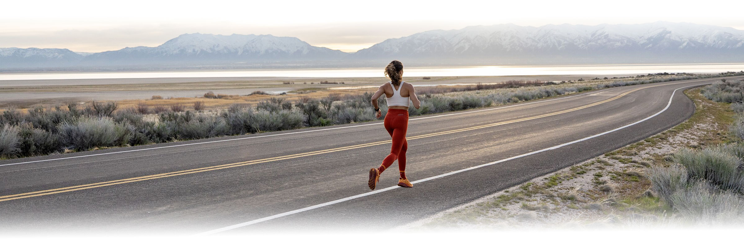 woman running on road in front of mountains